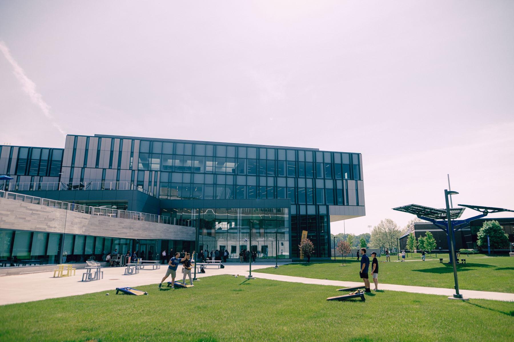 Four Kettering students play cornhole on the lawns in front of the Learning Commons